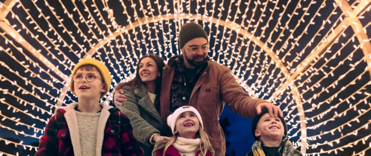 A family enjoying walking through a tunnel of twinkling lights during the Bay of Lights Festival in South Devon