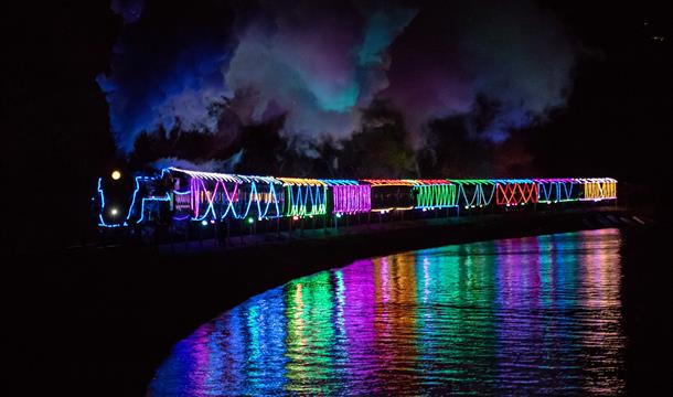 Train of Lights chugging along the track with the sea reflecting its Christmas lights