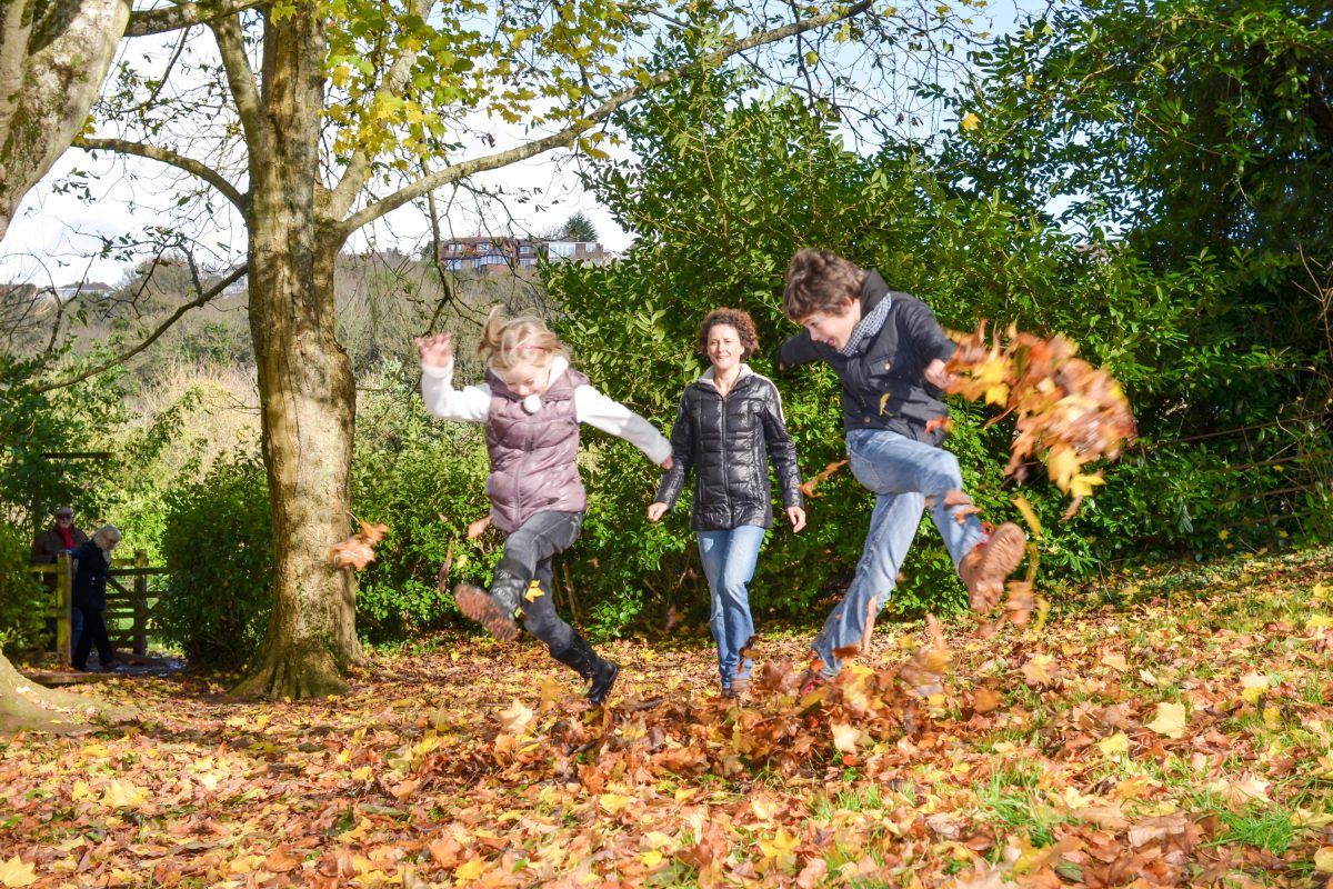 A family taking a walk through the woods kicking the gold and orange
autumnal leaves