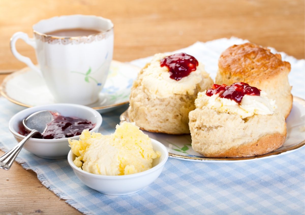 Traditional Devon Cream tea served with a cup of tea on a gingham tablecloth