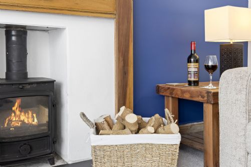 Welcoming holiday home lounge with a wood burner, log basket, and warm decor, perfect for creating a cosy, relaxing atmosphere