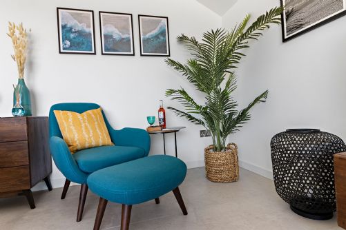 Inviting reading nook in a holiday home with plush armchair, footstool, and elegant decor creating a cosy, sophisticated atmosphere