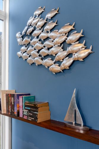 Charming nautical-themed holiday home decor with decorative fish wall art and a small boat ornament on a shelf