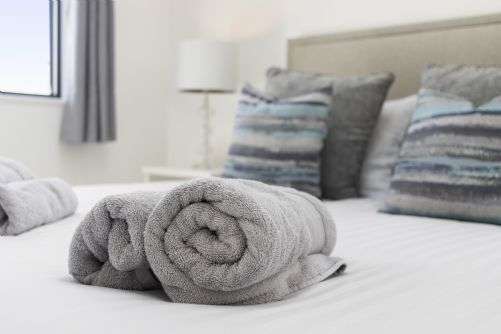 Stack of fresh towels on a bed ready for a new set of guests