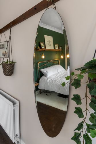 Stylish holiday home interior with a decorative mirror accented by hanging green foliage for a fresh, natural touch