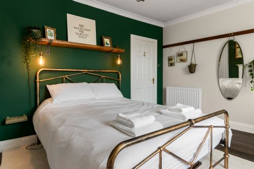 Elegant holiday home bedroom with crisp white bedding, plush pillows, and neatly arranged towels for a luxury hotel-style feel