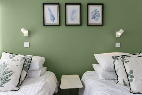 Tranquil holiday home bedroom decorated with green leaf cushions and natural accents, creating a calming countryside-inspired retreat