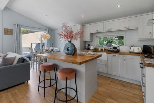 Bright, modern holiday home kitchen fully equipped with appliances, featuring a spacious breakfast bar for casual dining
