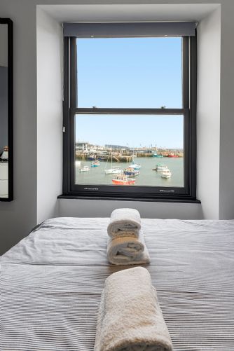 Luxurious holiday home bedroom with crisp white towels neatly folded on the bed to create a welcoming, hotel-style feel