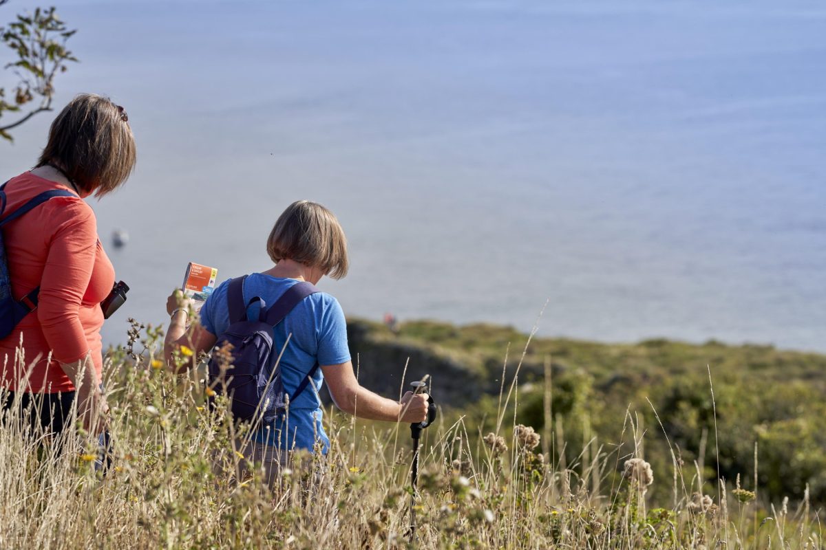 People taking a walk along the South West Coast Path with the grass swaying in the Autumn breeze