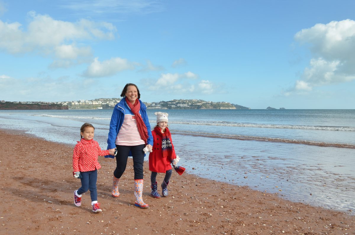A mum and two girls enjoying an Autumn walk along a South Devon beach