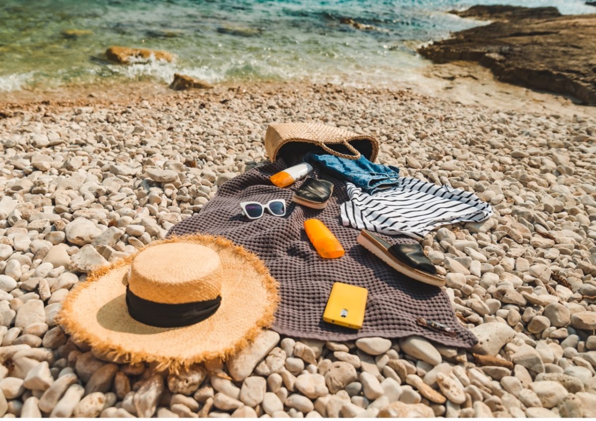 Towel laid on a pebble beach with all the essentials for a sunny day