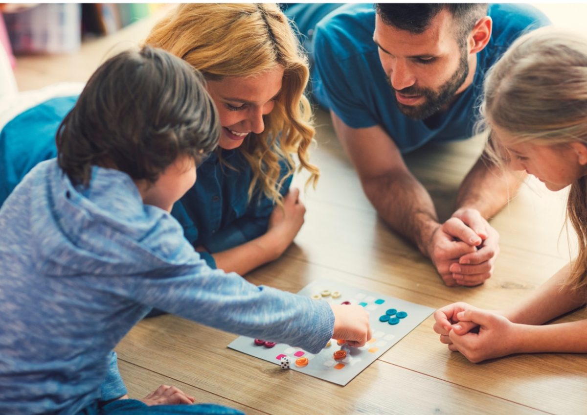 Family playing board games in a cosy holiday cottage living room.