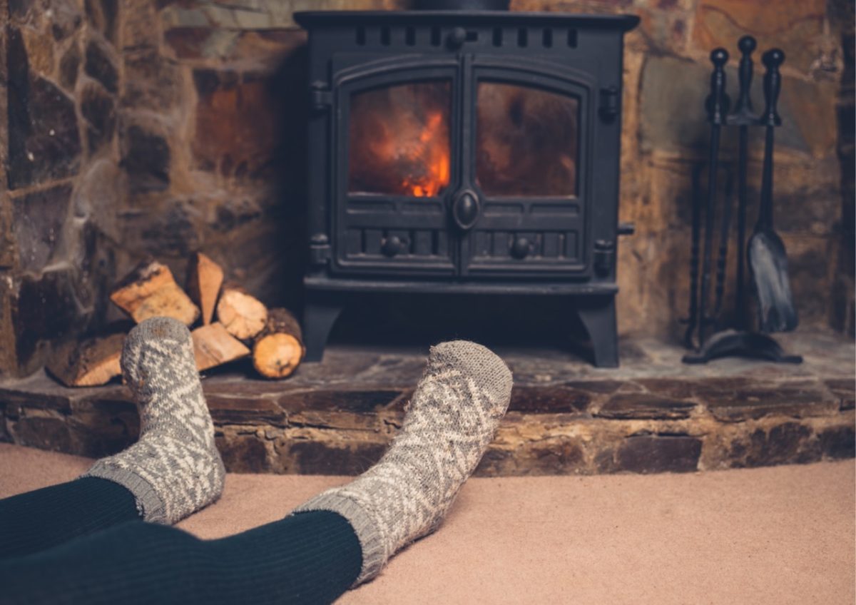 A guest warming up in front of a log burner in one of our South Devon holiday homes