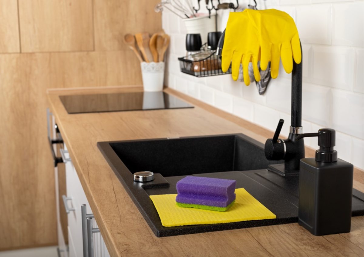 A kitchen sink with washing up liquid, rubber gloves, sponge and washcloth in a holiday home in South Devon