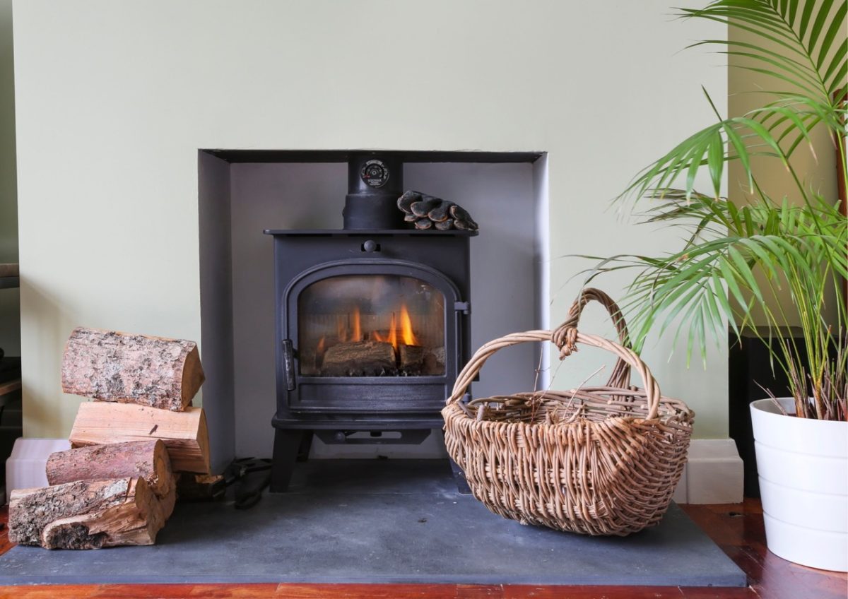 A warming log fire with a basket of kindling in a holiday home in South Devon