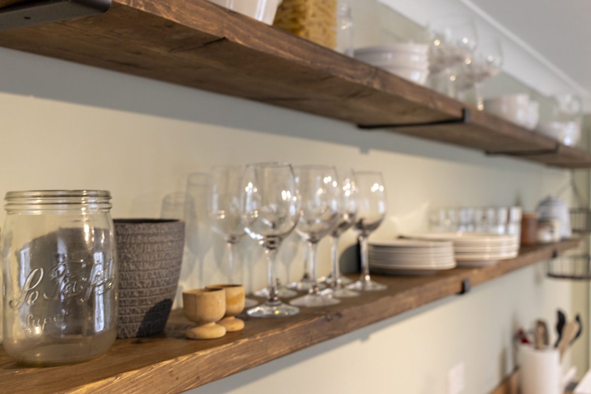 Shelves of wine glasses and crockery in a kitchen of a holiday home in South Devon