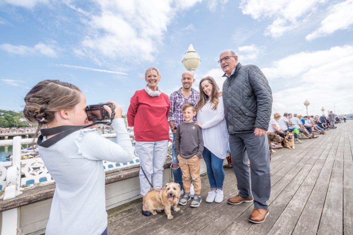 Little girl taking photos of her family and dog on a South Devon pier