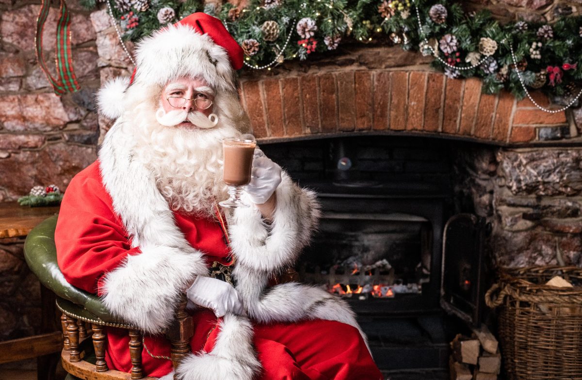 Santa sat by a fire enjoying a Hot Chocolate in Kents Cavern as part of the Bay of Lights Festival in South Devon