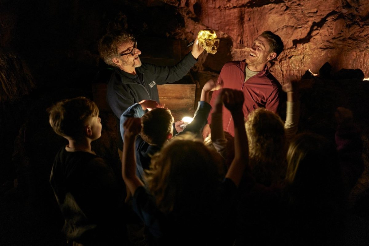 A group of visitors to Kents Cavern learning about the humans that used to live in these ancient caves