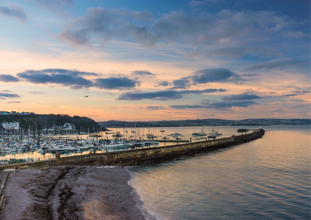 View of Brixham Breakwater and Tor Bay from Breakwater Beach in South Devon on a chilly winter afternoon, with waves lapping against the shore.