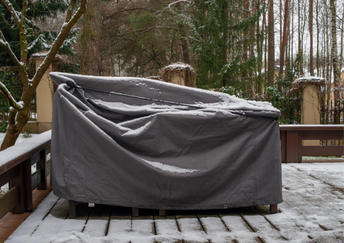Outdoor patio furniture covered and protected for winter with snow in a Devon holiday let garden.