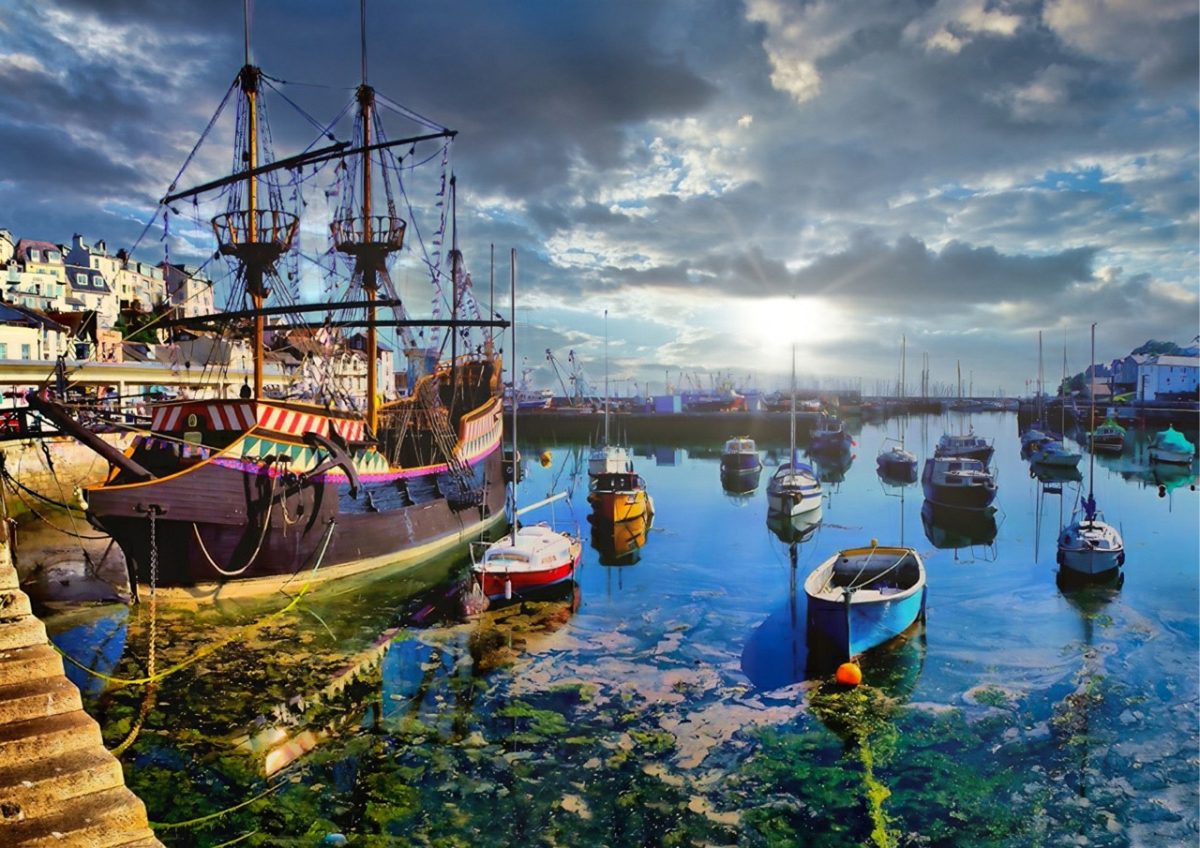 The Golden Hind replica ship moored in Brixham Harbour as the sun rises on a crisp winter morning, casting golden light over the water.