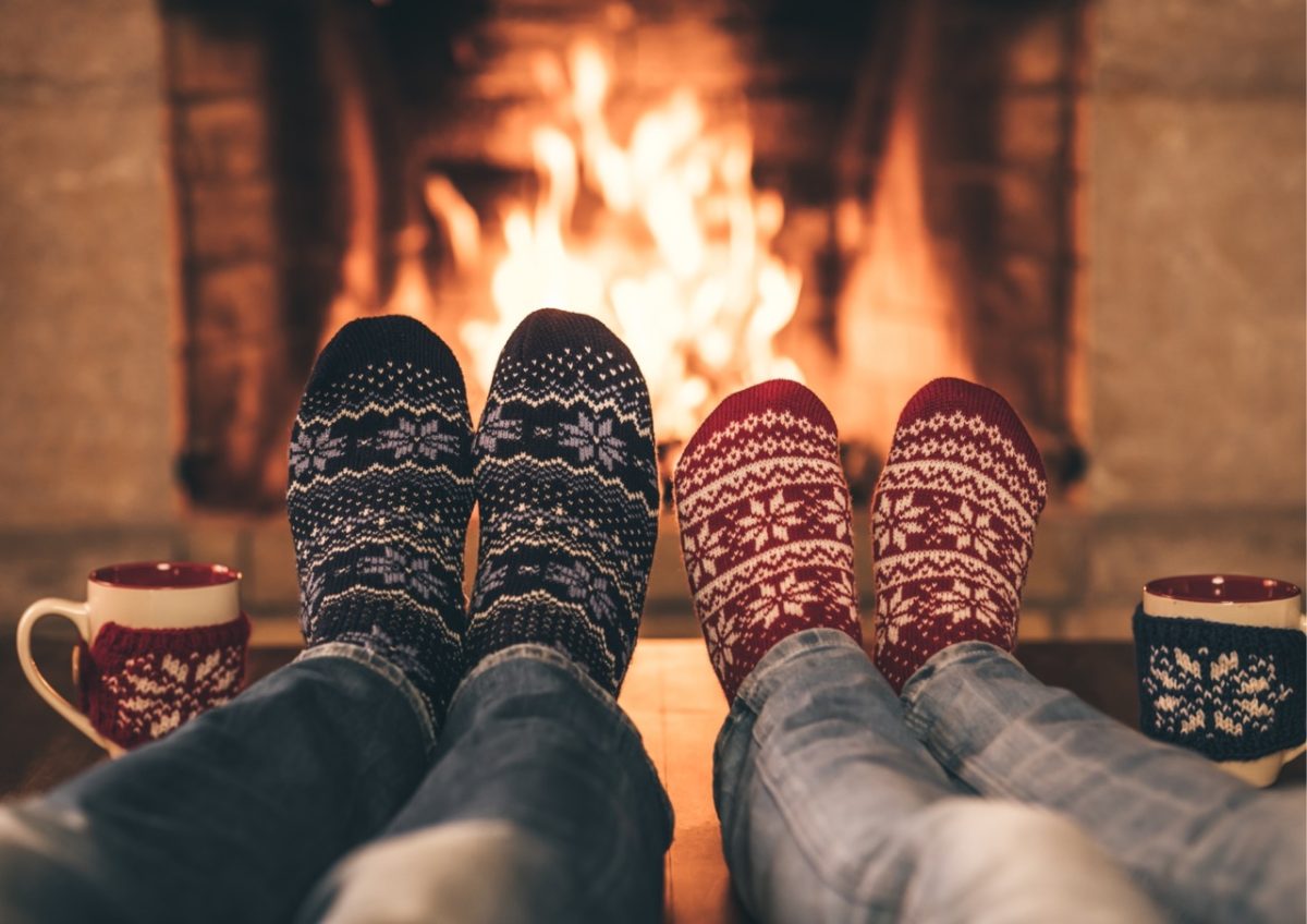 A couple warming their feet by the fire in a holiday home in South Devon
